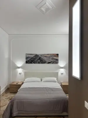 a white bedroom with a large bed and two night stands at Appartamento San Vito in Piana degli Albanesi