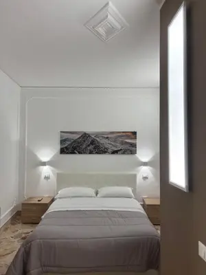 a white bedroom with a large bed and two windows at Appartamento San Vito in Piana degli Albanesi