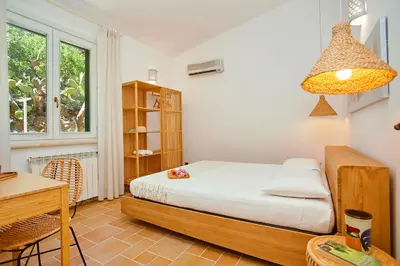 a bedroom with a bed and a desk and a window at Villa Lo Zingaro - Scopello-Villas in Scopello