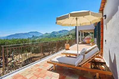 a patio with a table and an umbrella and chairs at Villa Lo Zingaro - Scopello-Villas in Scopello