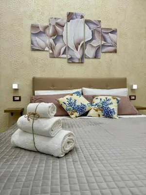 a bedroom with a bed with four paintings on it at Casetta Philia - Castellammare del Golfo in Castellammare del Golfo