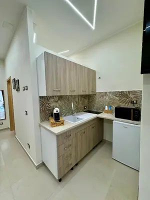 a kitchen with wooden cabinets and a sink and a refrigerator at Casetta Philia - Castellammare del Golfo in Castellammare del Golfo