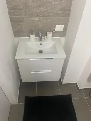 a white sink in a bathroom with a black rug at Giuse home in Palermo