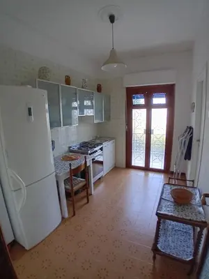 a kitchen with a white refrigerator and a table at ai colori di Giggia in Isola delle Femmine