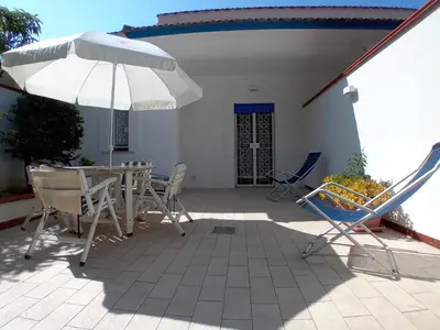 a patio with a table and chairs and an umbrella at ai colori di Giggia in Isola delle Femmine