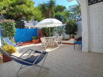 a patio with a table and chairs and an umbrella at ai colori di Giggia in Isola delle Femmine
