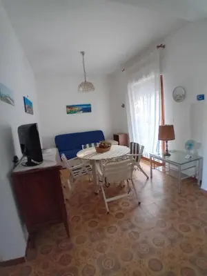 a living room with a table and a blue couch at ai colori di Giggia in Isola delle Femmine