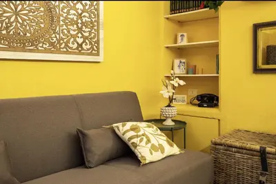 a yellow room with a couch and a vase of flowers at NanaHouse Cozy apt in Corso Vittorio Emanuele in Palermo