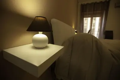 a white lamp on a table next to a bed at Due Passi in Palermo