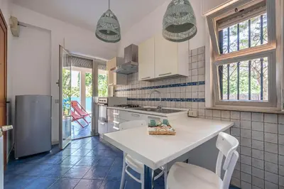 a kitchen with a white counter and chairs in it at Hola House Mondello in Lido di Mondello