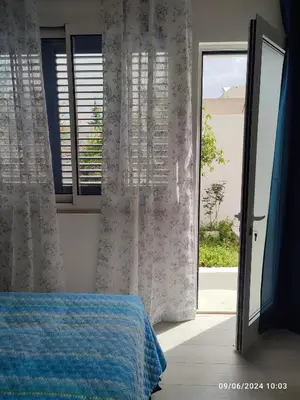 a bedroom with a bed with a blue blanket and windows at Tramonti d'Alba in Terrasini
