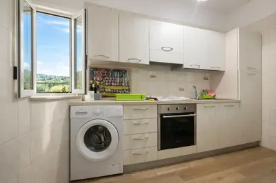 a white kitchen with a washing machine in it at Nichi & Matti Iemmolo's Guest House in Campofelice di Roccella