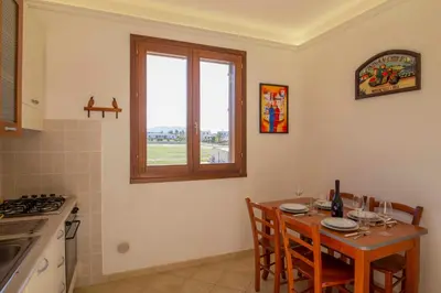a kitchen with a table with chairs and a window at Residence Hotel Marino Tourist in San Vito lo Capo