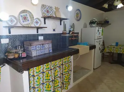 a kitchen with a counter with plates and a refrigerator at Rifugio Riserva Grotta Mazzamuto in Altavilla Milicia