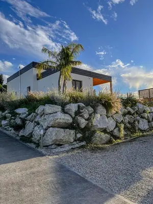 a building with a palm tree and a stone wall at Villa Ginevra in Santa Ninfa