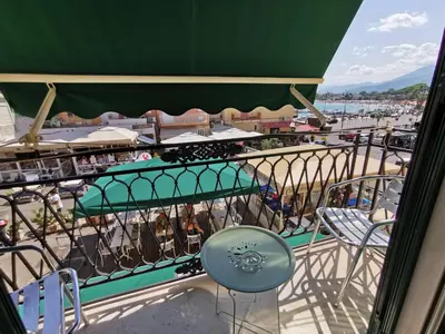 a balcony with chairs and tables and a view of a harbor at Appartamento Tirreno Mondello in Palermo