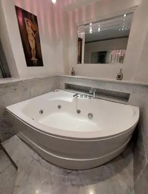 a large white tub in a bathroom with a mirror at Oasis Green Villa in Palermo