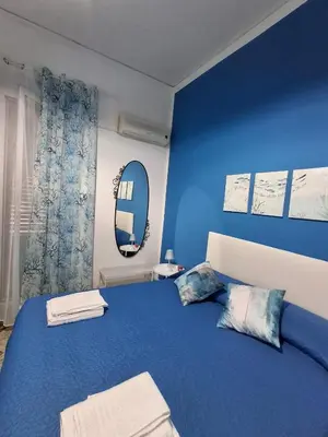 a blue bedroom with a bed and a mirror at La Casa di Giovy in Palermo