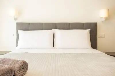 a bedroom with a bed with white sheets and pillows at Luxury Villa Leto in Palermo