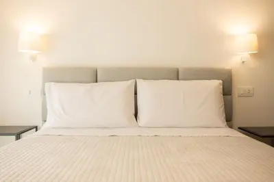 a bed with two white pillows and two lamps at Luxury Villa Artemis Mondello in Palermo