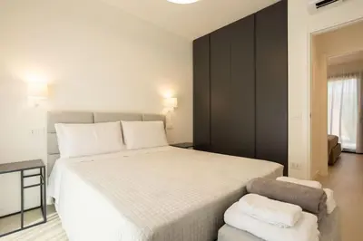 a bedroom with a large white bed and a chair at Luxury Villa Artemis Mondello in Palermo