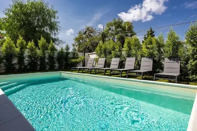 a swimming pool with white chairs next to a house at Luxury Jacuzzi Villa Atena in Palermo