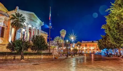 a building with a flag in front of it at night at mastro casa vacanza in Palermo