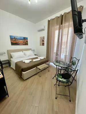 a bedroom with a bed and a table and a television at Bieddu Suites - Palermo City Center in Palermo