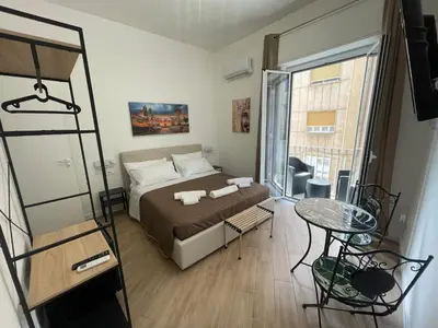 a bedroom with a bed and a table and a window at Bieddu Suites - Palermo City Center in Palermo