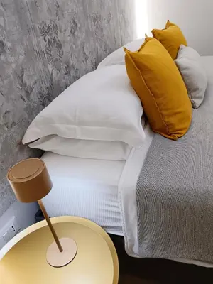 a bed with white and yellow pillows and a table at Kalos suite in Palermo