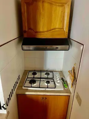 a kitchen with a stove and a wooden cabinet at Fra centro & mare in Palermo