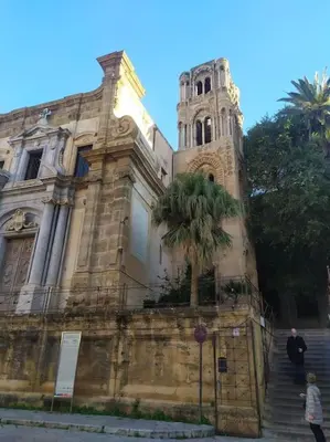 a building with a tower and a palm tree in front at Fra centro & mare in Palermo