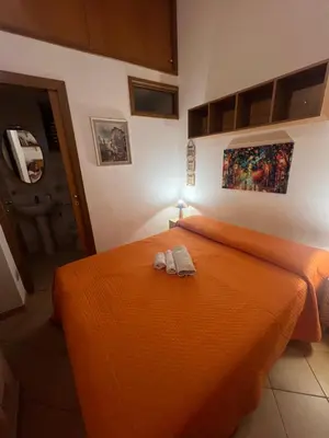 a bedroom with an orange bed with two slippers on it at Fra centro & mare in Palermo