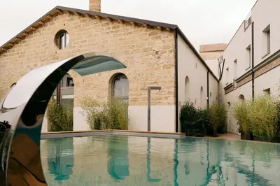 a swimming pool in front of a brick building at Spasimo Hôtellerie in Palermo