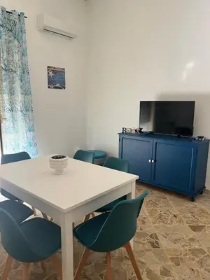 a dining room with a white table and blue chairs at Vito's holiday house in Palermo