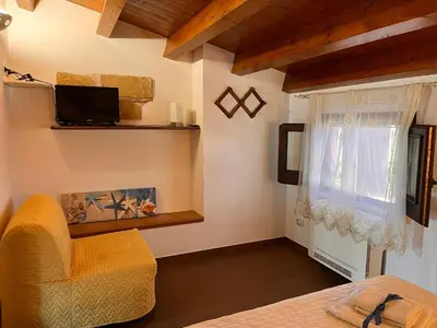 a bedroom with a bed and a chair and a window at Rustico San Leonardo in Cinisi