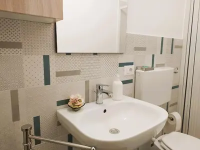 a bathroom with a white sink and a toilet at La Rugiada-con giardino e parcheggio moto privato in Alcamo