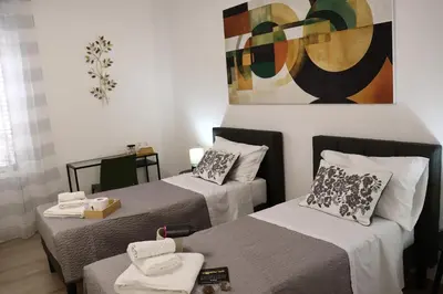 two beds in a room with a painting on the wall at Palermo Mia in Palermo