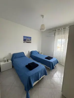 two beds in a white room with blue sheets at La Bella Vista in Palermo