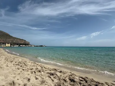 a sandy beach with the ocean and buildings in the background at La Bella Vista in Palermo