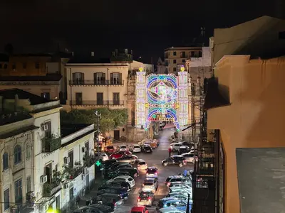 a busy city street with a large carnival arch at night at Aurora house in Palermo
