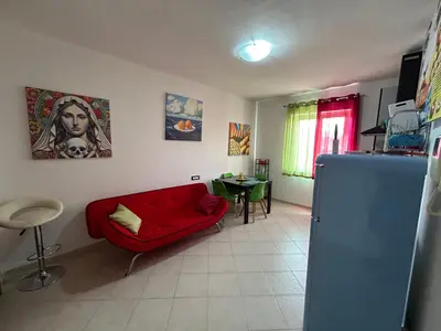 a living room with a red couch and a table at Aurora house in Palermo