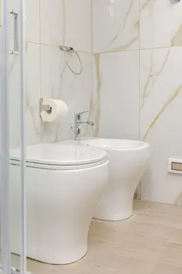 a white bathroom with a toilet and a sink at Stella del Sud in Palermo