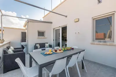 a dining room and living room with a table and chairs at La Dolce Vista - Magaggiari in Terrasini