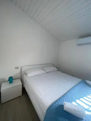 a white bedroom with a bed and a night stand at La Maiolica 59 in Terrasini