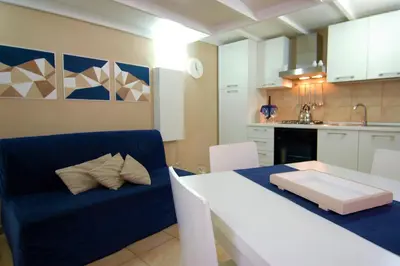 a living room with a blue couch and a kitchen at Virna House a Castellammare del Golfo in Castellammare del Golfo