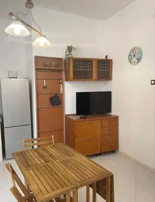 a kitchen with a table and a television and a refrigerator at Casa Visconti 170mq-centro storico in Palermo