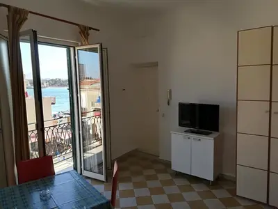 a room with a table and a television and a balcony at Appartamento Mediterraneo Mondello in Palermo
