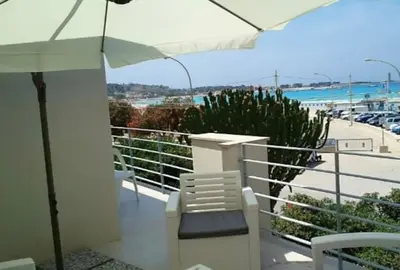 a balcony with an umbrella and chairs and a view of the beach at Villa Luxury Fronte mare San Vito lo Capo in San Vito lo Capo