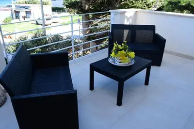 two chairs and a table with a plate of flowers on a balcony at Villa Luxury Fronte mare San Vito lo Capo in San Vito lo Capo